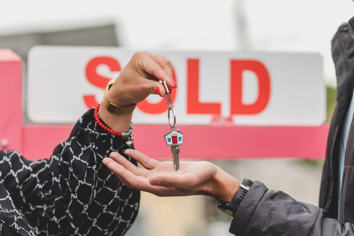 Keys handed over beside a sold sign